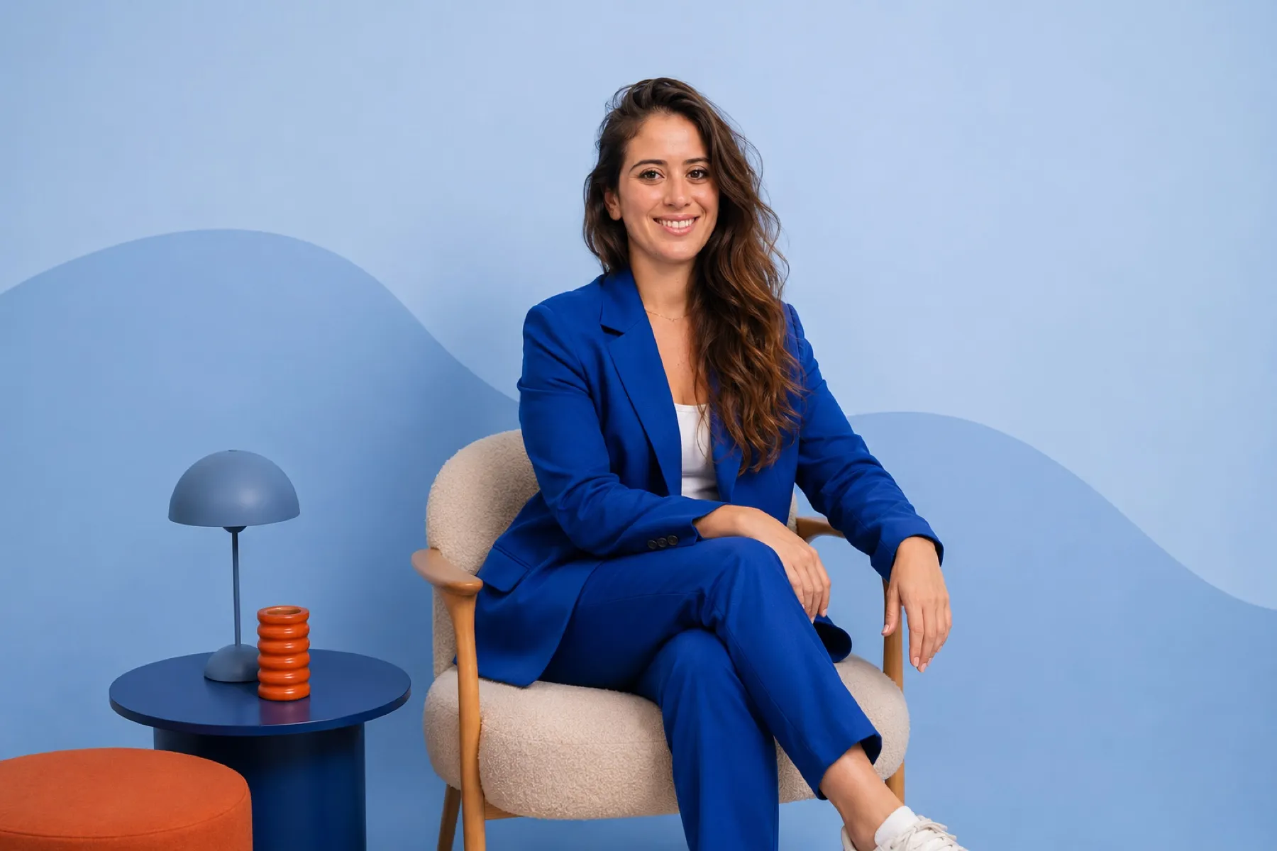 Coline Deglin, costume bleu, assise dans un décor bleu et orange